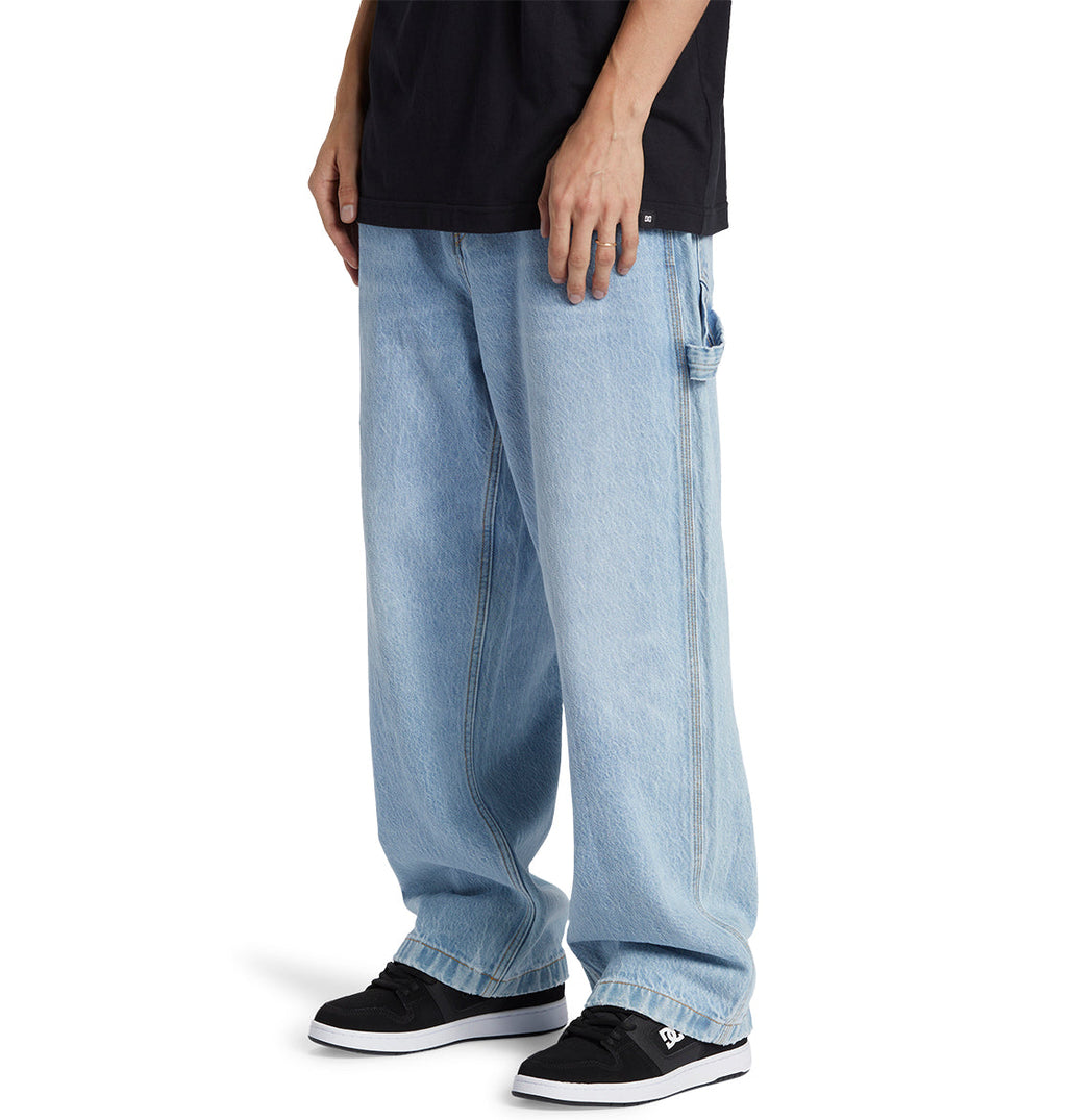 Outfitted in DC Shoes’ Men’s Worker Baggy Carpenter Ril Jeans featuring contrast stitching, styled with a black t-shirt and black DC sneakers with white soles—this look perfectly channels skate culture jeans style.