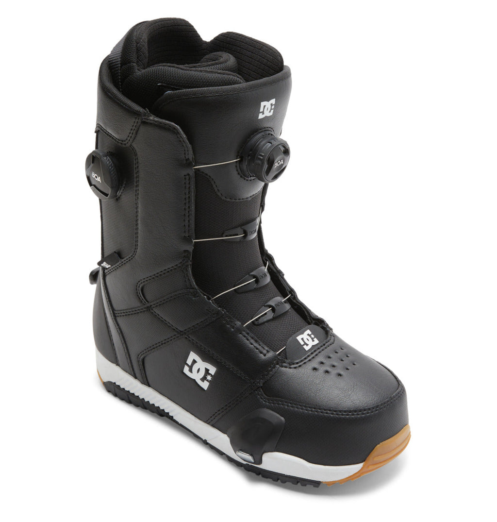 A pair of DC Shoes Men’s Control Step On BOA® Snowboard Boots in black, showcasing the Dual Zone BOA® Fit System for advanced performance, with a white DC logo and brown rubber sole, displayed at an angle on a white background.