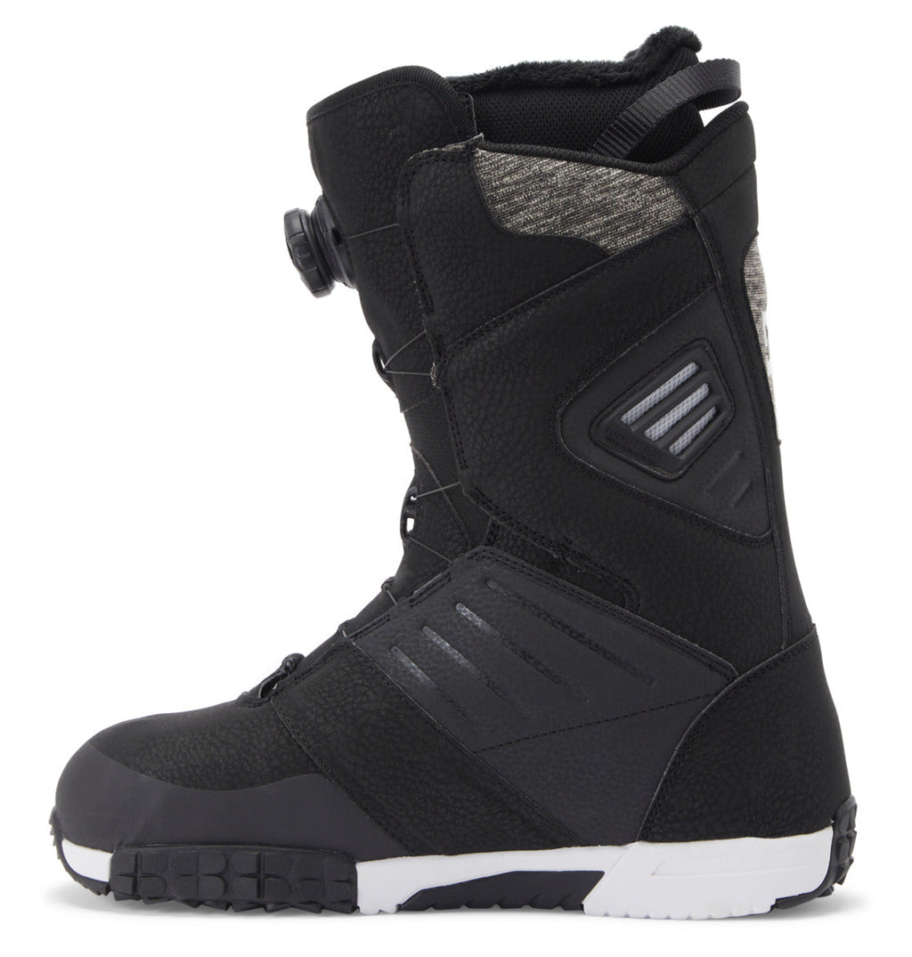 A left side profile of the DC Shoes Men’s Judge BOA® Snowboard Boot is shown on a white background, featuring black textured panels, a white and black Vibram outsole, and a Dual Zone BOA® Fit System dial closure.