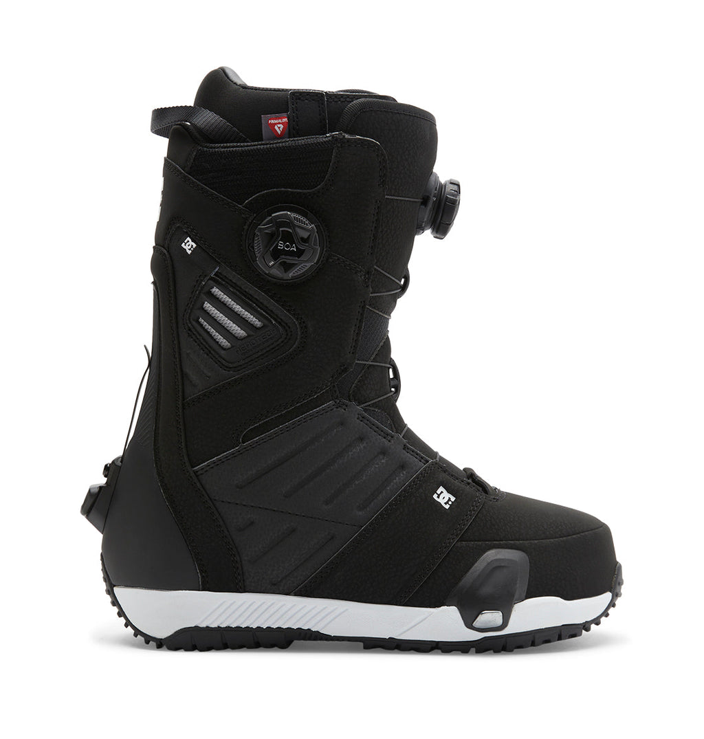 A side-profile image of the DC Shoes Men’s Judge Step On® Snowboard Boots is shown in black with a white sole, featuring the Dual Zone BOA Fit System lacing, distinctive side detailing, and padded ankle support against a white background.