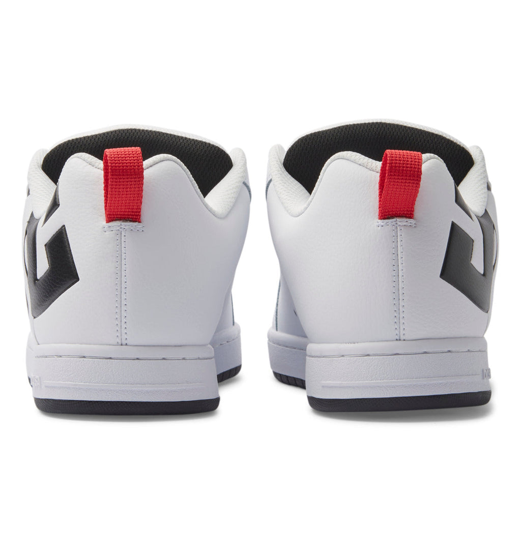 A pair of DC Shoes Men’s Court Graffik Shoes in white, shown from the back, showcasing bold black geometric designs on the sides, red pull tabs on the heels, and a distinctive two-tone sole for extra style.