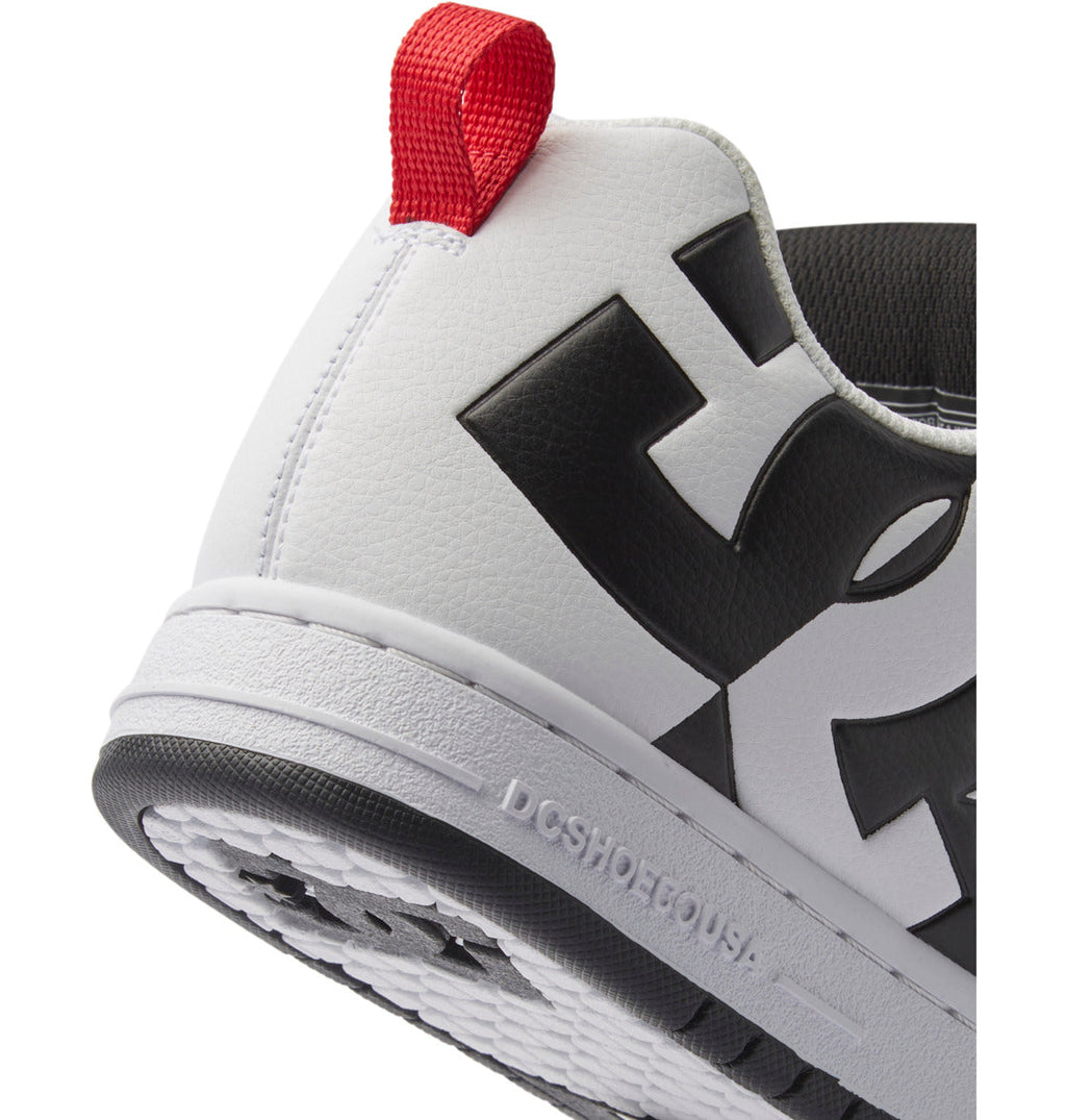 Close-up of the heel of the DC Shoes Men’s Court Graffik Shoes, featuring a white upper with a red pull tab, black lettering, DCSHOESCOUSA embossed on the two-tone sole, and showcasing the iconic DC Star Logo.