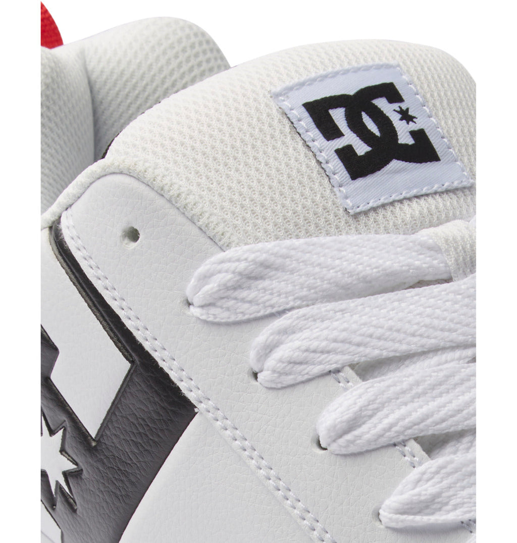 Close-up of the DC Shoes Men’s Court Graffik Shoes in white, featuring white laces, black accents, and a DC Shoes logo patch on the tongue. This men’s sneaker boasts a stylish two-tone sole and showcases the iconic DC Star Logo for added appeal.