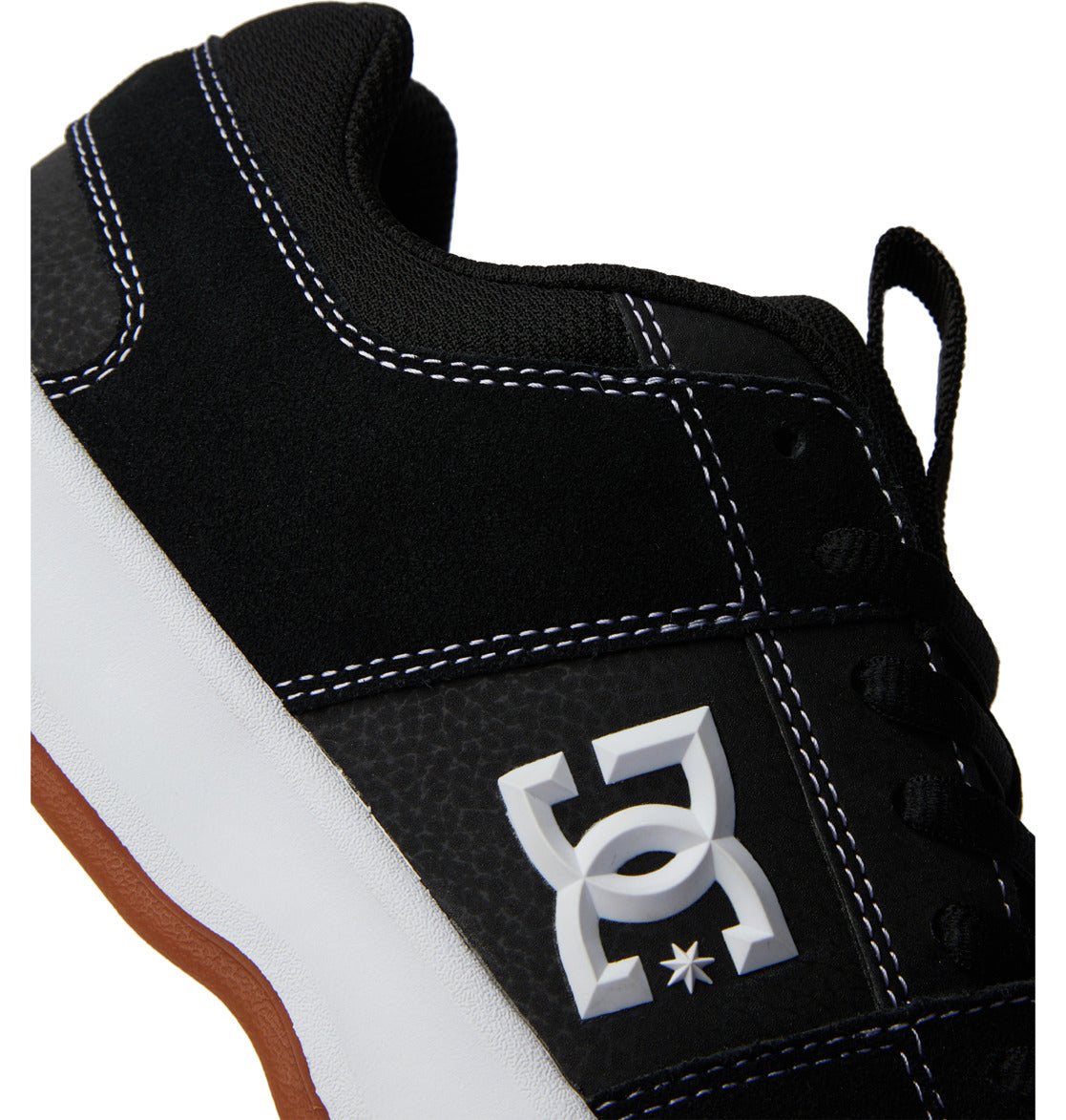 Close-up of the DC Shoes Men’s Lynx Zero Shoes in black and white with a gum sole, showcasing the signature white DC logo on the side panel and contrasting white stitching details.