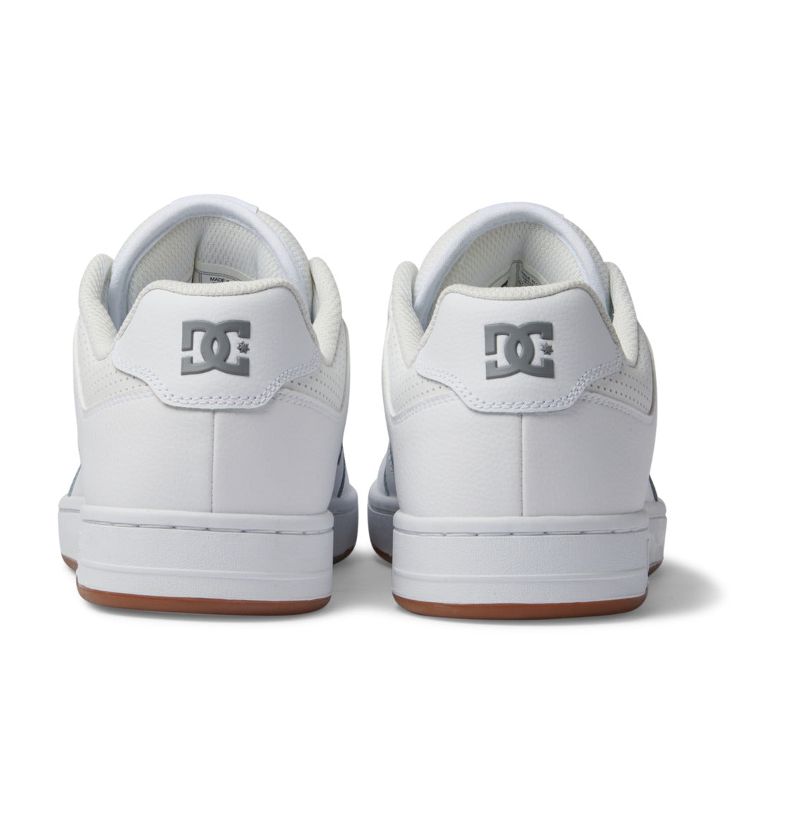 Back view of the Men’s Manteca 4 Shoes by DC Shoes in white with gray DC logos on the heels, white midsoles, and light brown outsoles, set against a plain white background.