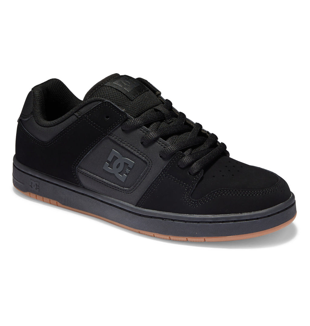 The Men’s Manteca 4 Shoes by DC Shoes feature a low-top design in black with matching black laces, complemented by a gray sole with a brown bottom. The DC logo appears on both the side and tongue, offering a classic skate style combined with modern comfort for everyday wear.