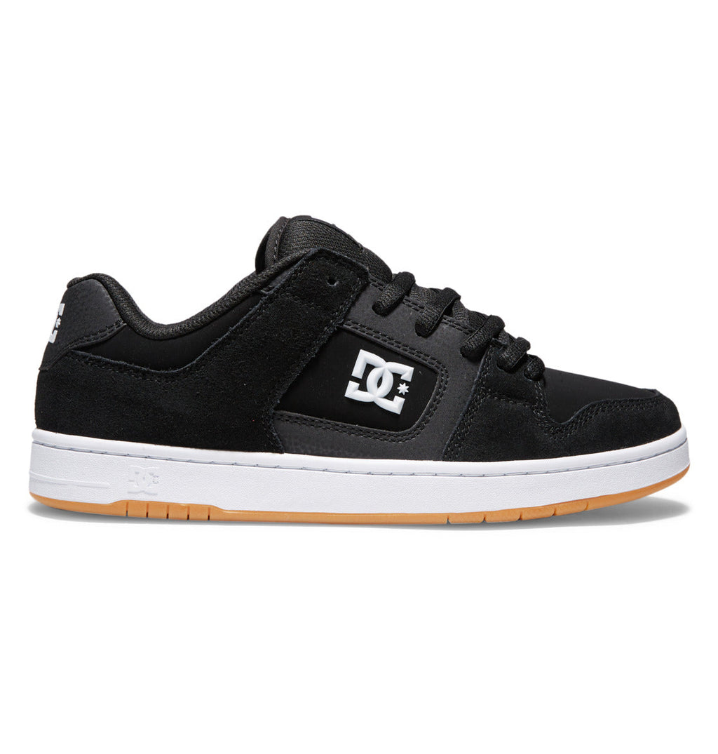 The image displays the DC Shoes Men’s Manteca 4 Skate Shoes in black, featuring a white DC logo on the side, black laces, a durable cupsole, white midsole, and a light brown gum outsole with added impact protection insoles, shown in a side profile view against a white background.