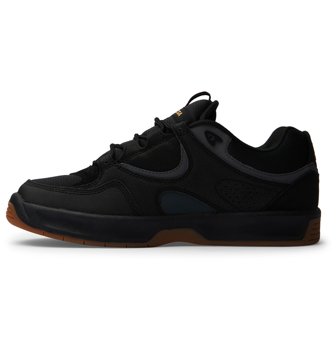 A black, low-profile athletic sneaker—the Men’s Kalynx Zero Shoes by DC Shoes—features mesh and leather accents, black laces, and a brown rubber sole. Shown in profile against a white background.