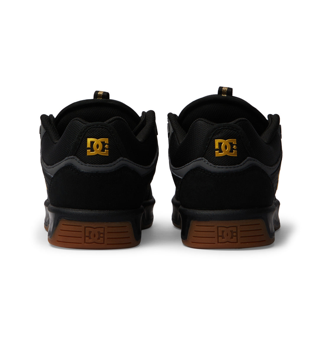 Back view of black Men’s Kalynx Zero Shoes by DC Shoes, featuring brown gum soles and gold DC branding on the heels, positioned side by side against a white background.