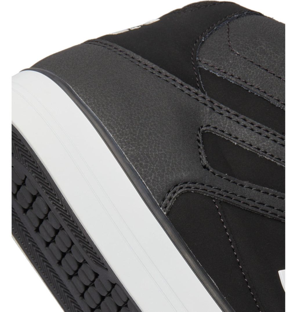 Close-up of the heel and part of the sole of a black Men’s Pure High-Top Shoe by DC Shoes, featuring a white midsole, visible stitching, and a textured rubber outsole—designed for both style and durability.