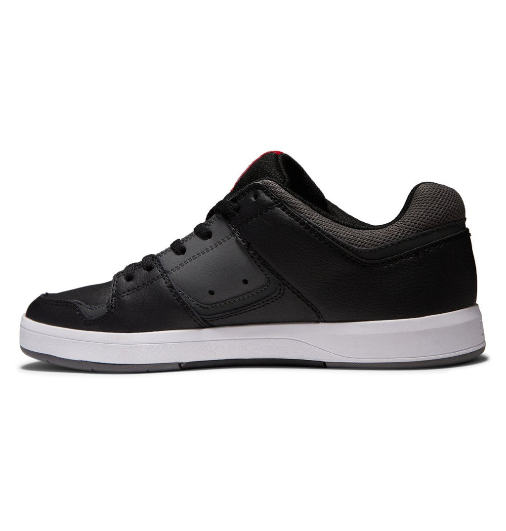 A side view of the Men’s DC Cure Shoes by DC Shoes: black low-top sneakers with matching black laces, a light gray sole, and a padded ankle collar crafted from premium leather nubuck, displayed against a white background—ideal for everyday wear or enthusiasts of the signature DC Shoes style.