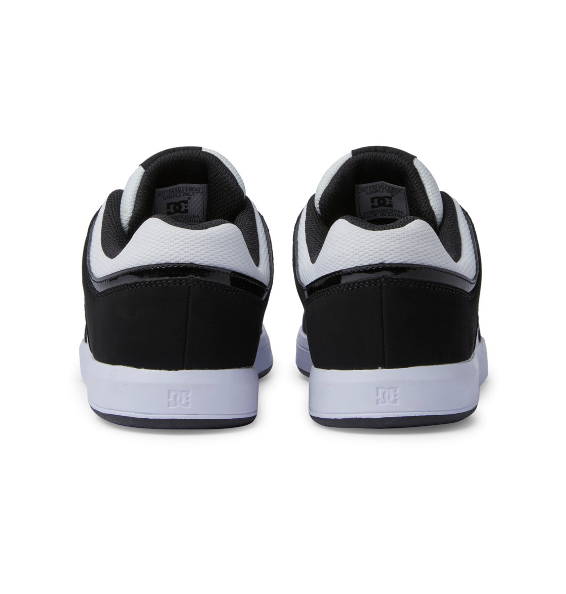 A pair of Men’s DC Cure Shoes by DC Shoes in a black and white colorway, displayed from the back, featuring a leather upper with white soles and the distinct DC Shoes logo on both the heel and inner lining—making them an ideal choice for stylish everyday wear.