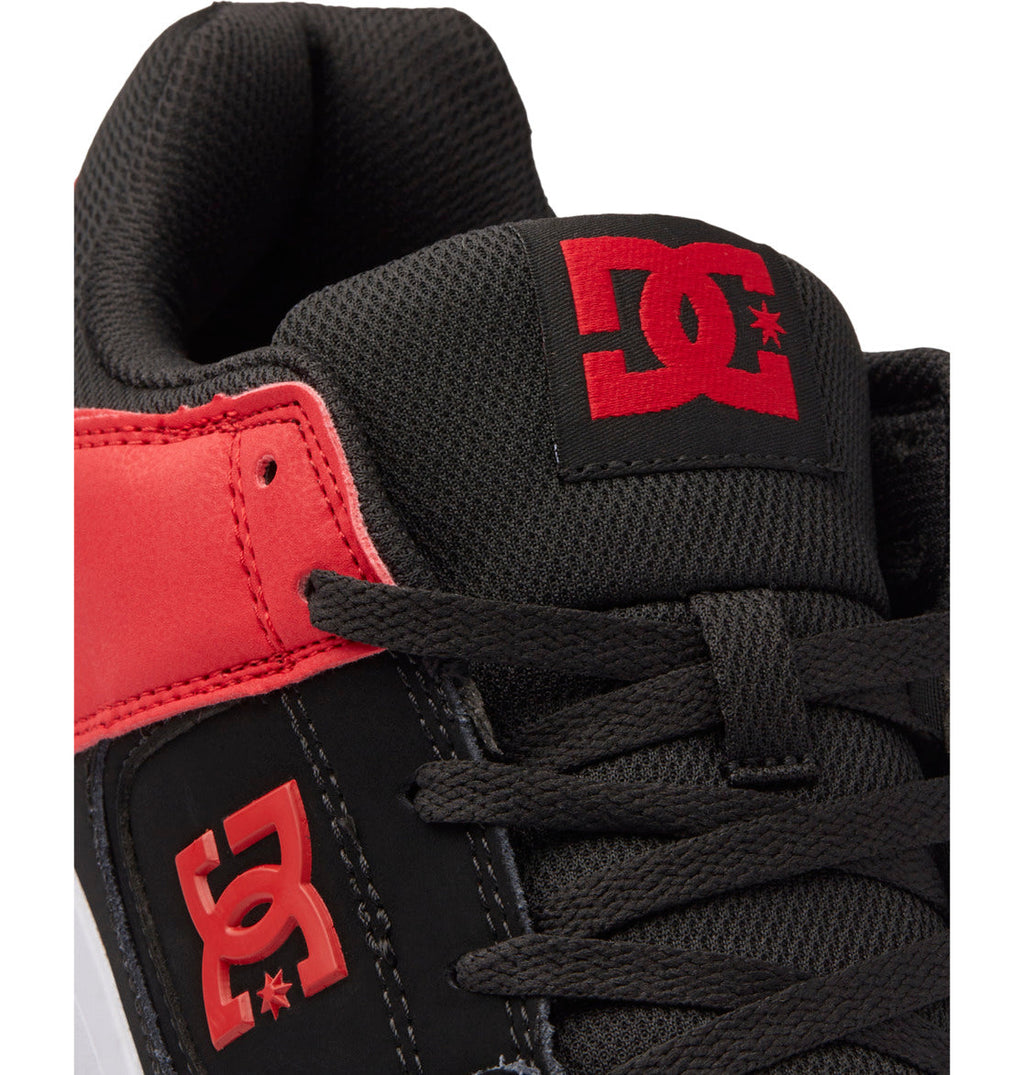 Close-up of the Men’s DC Cure Shoes by DC Shoes in black and red, highlighting the tongue and side featuring the signature red DC Shoes logo. Crafted with a durable leather upper and mesh accents, these shoes are finished with black laces and detailed stitching—making them ideal for everyday wear.