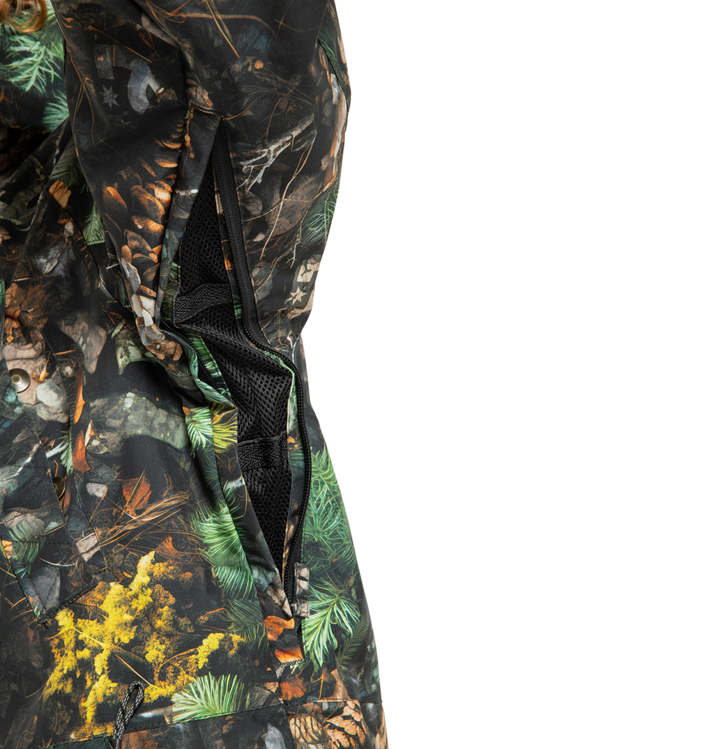Close-up of the DC Shoes Men’s Tundra Insulated Jacket, featuring an eco-friendly design with a camouflage pattern composed of green, brown, and yellow leaves, branches, and pine needles. The image highlights an open zippered vent lined with black mesh fabric.