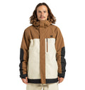 A person is wearing the DC Shoes Men’s Defiant Insulated Snow Jacket, featuring brown and beige colors with black accents, standing facing forward with arms at their sides against a plain white background.