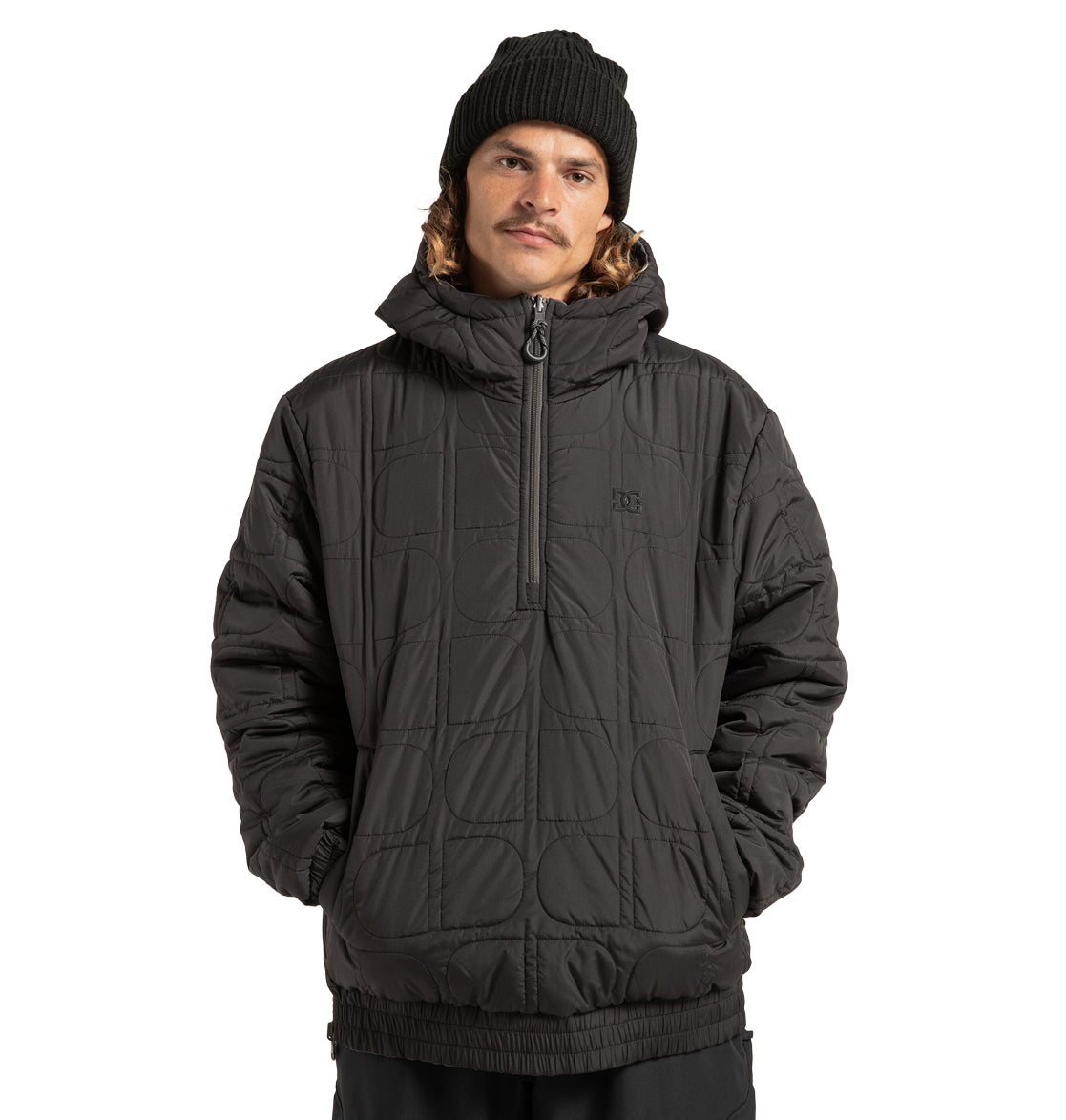 A person wearing a black beanie and the DC Shoes Unisex Nexus Reversible Insulated Anorak Jacket with a half-zip, standing with hands in pockets against a white background.