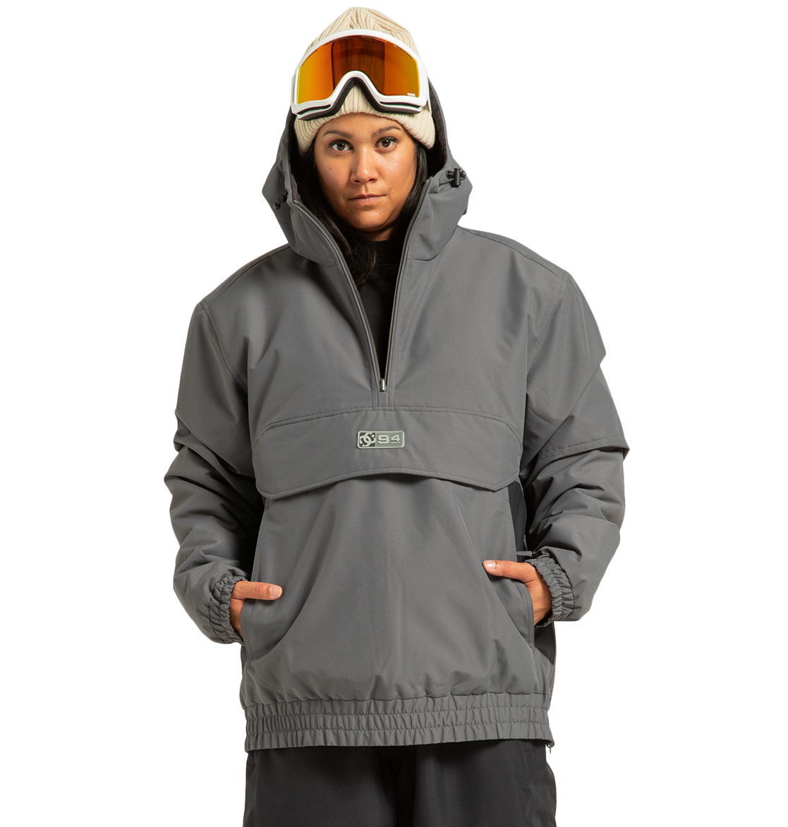 A person wearing the DC Shoes Unisex Nexus Reversible Insulated Anorak Jacket in gray, paired with a tan beanie and ski goggles, stands with hands in pockets against a plain white background.