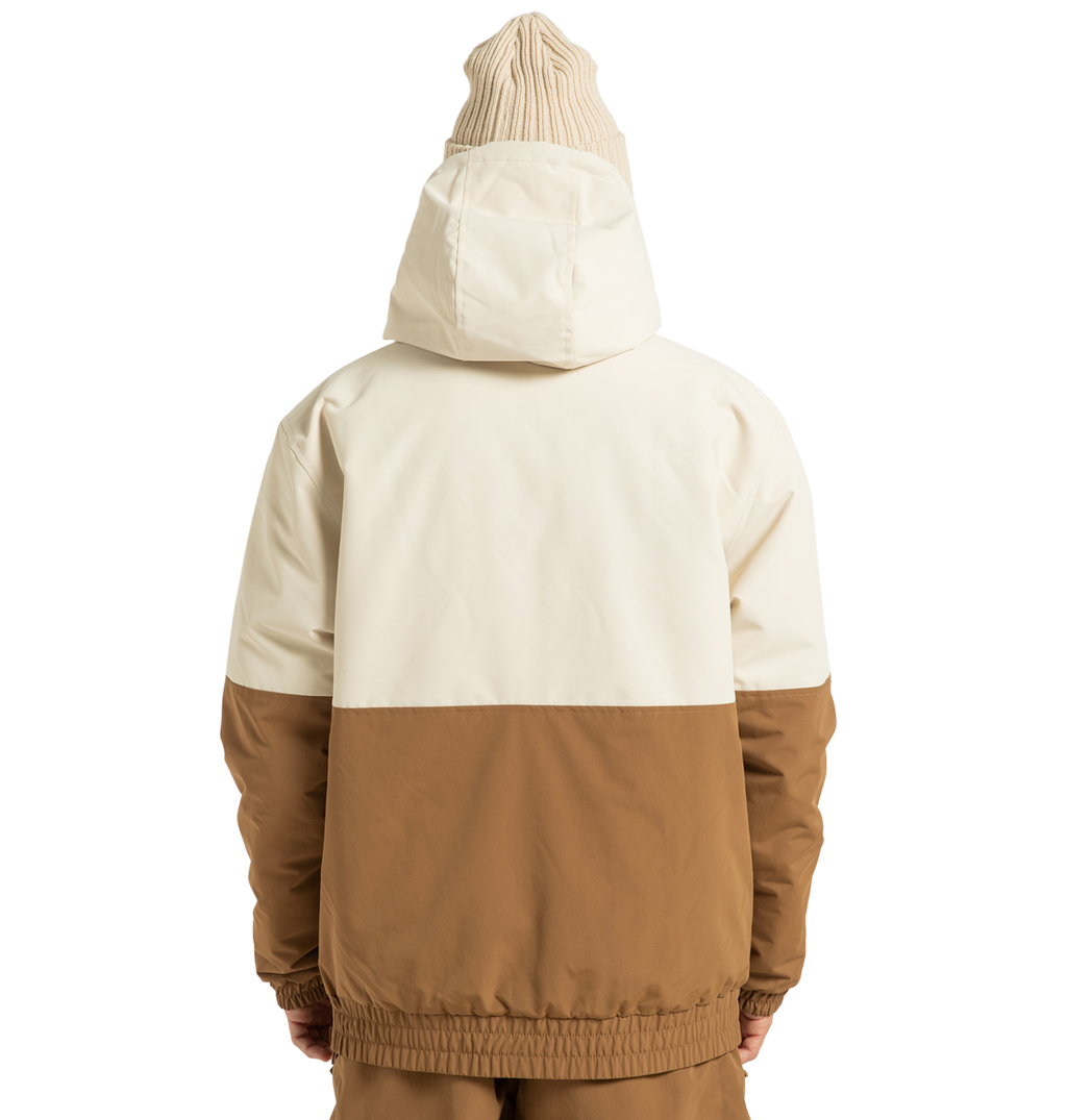 A person stands facing away against a plain white background, wearing the DC Shoes Unisex Nexus Reversible Insulated Anorak Jacket in cream and brown—crafted from recycled polyester—paired with a beige knit beanie and matching brown pants, creating the perfect look for any outdoor adventure.