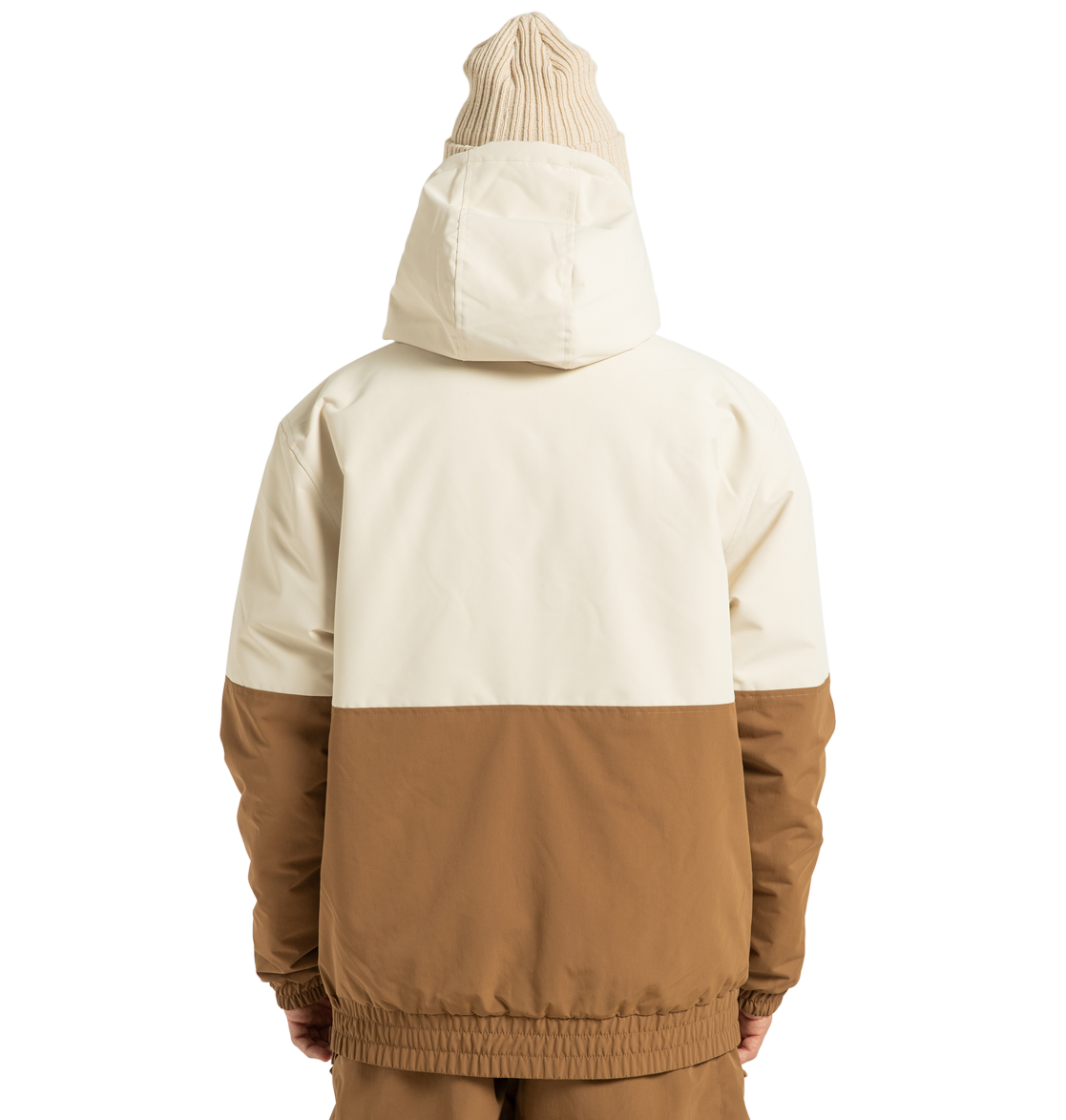 A person stands facing away against a plain white background, wearing the DC Shoes Unisex Nexus Reversible Insulated Anorak Jacket in cream and brown—crafted from recycled polyester—paired with a beige knit beanie and matching brown pants, creating the perfect look for any outdoor adventure.