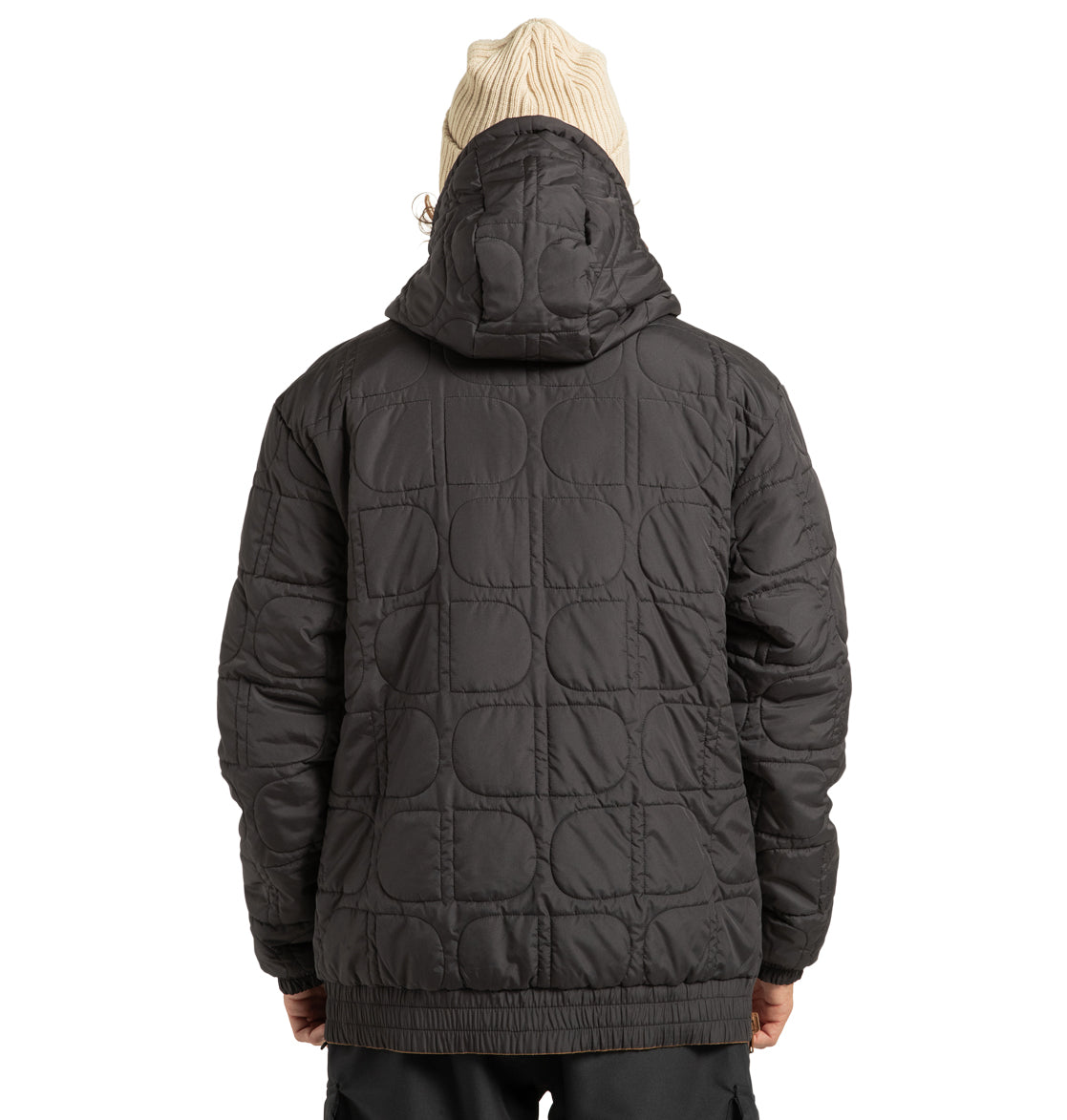 A person is seen from behind against a plain white background, wearing the DC Shoes Unisex Nexus Reversible Insulated Anorak Jacket—a black quilted hooded design with a geometric pattern, crafted from recycled polyester—and a beige knit beanie. This versatile jacket is ideal for any outdoor adventure.