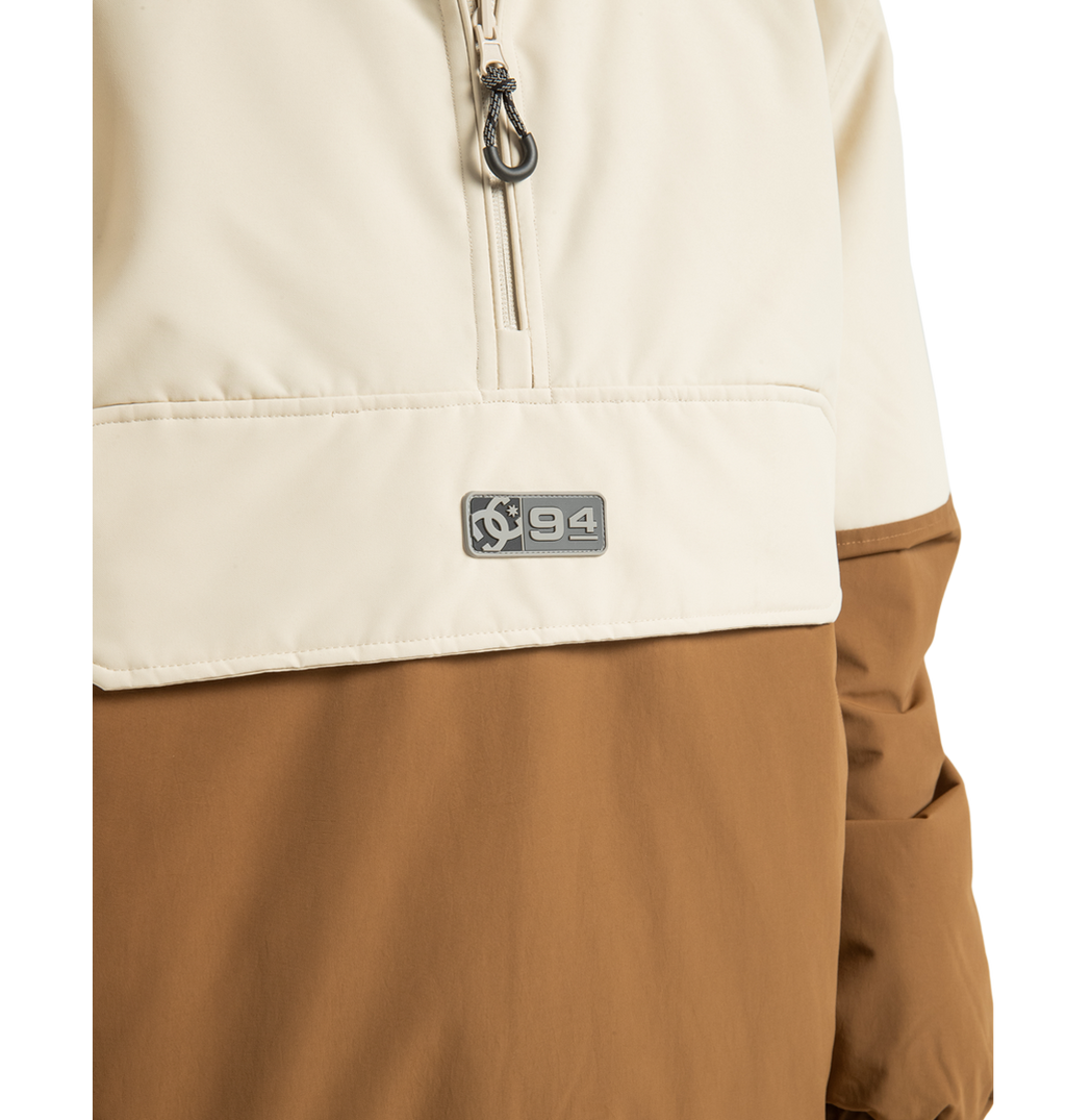 Close-up of the Unisex Nexus Reversible Insulated Anorak Jacket by DC Shoes, shown here in a cream and brown color-block design with a partial zipper and a small ‘94’ logo patch on the chest—ideal for your next outdoor adventure.