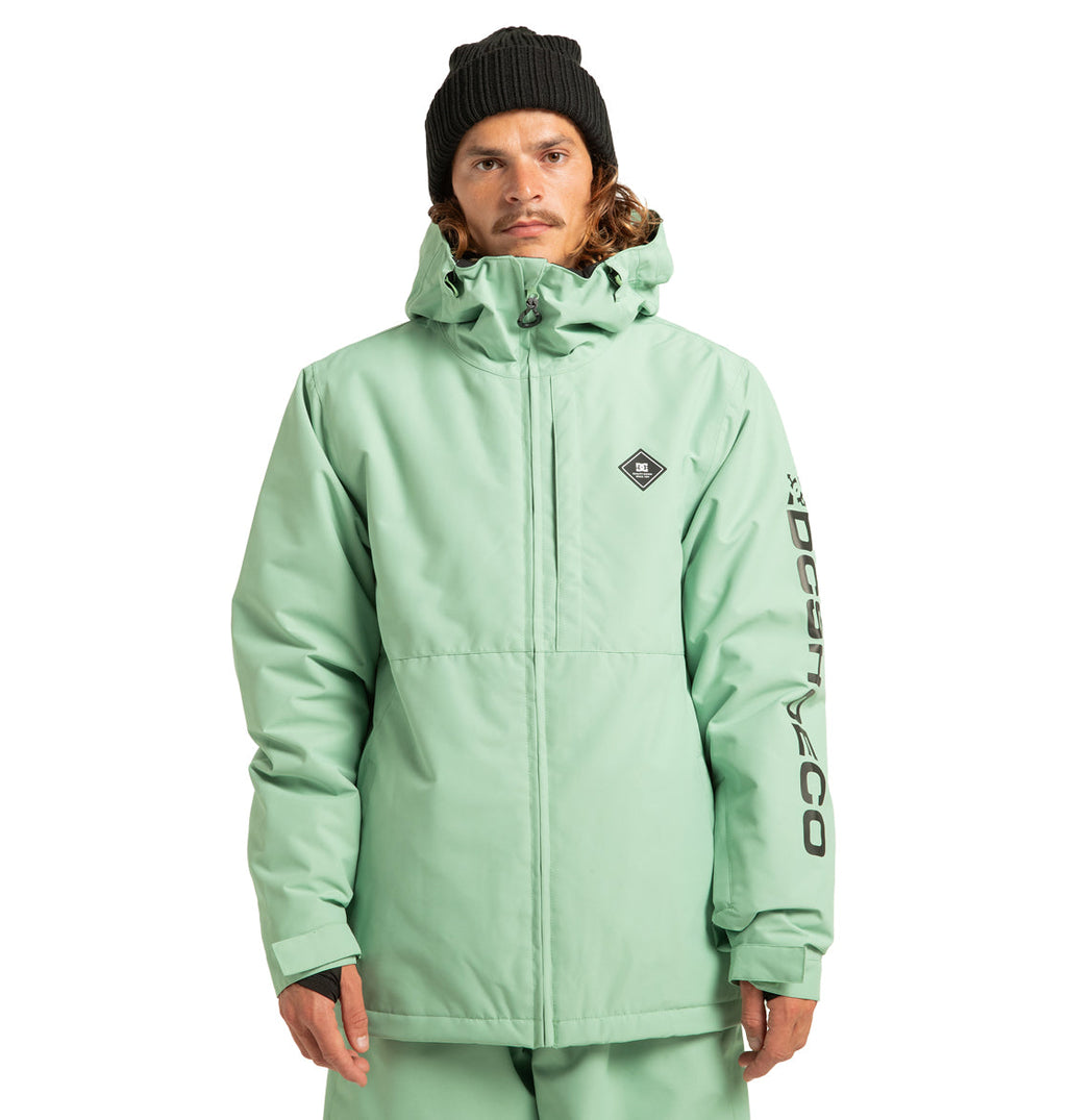 A person wearing the DC Shoes Unisex Basis Insulated Jacket in mint green, paired with matching pants and a black beanie, stands facing forward. This winter jacket, ideal for cold-weather activities, features a logo on the chest and text on the left sleeve. Made from recycled polyester, it offers both style and sustainability.