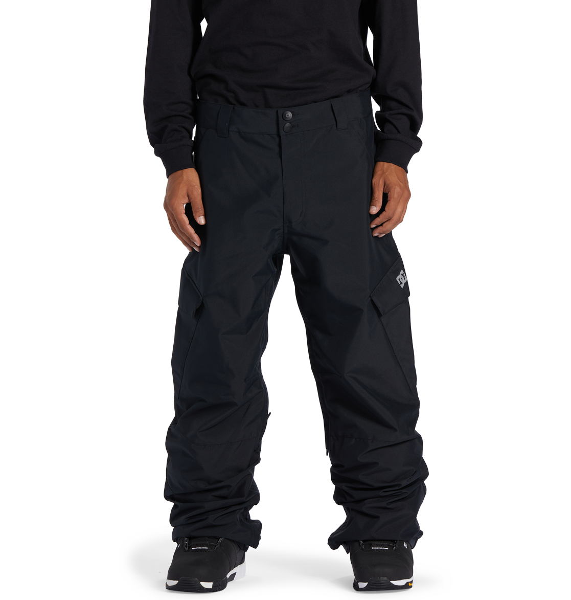 A person wearing loose-fitting DC Shoes Men’s Banshee Insulated Pants, a long-sleeve black shirt, and black sneakers stands facing forward against a white background, showcasing essential winter gear.