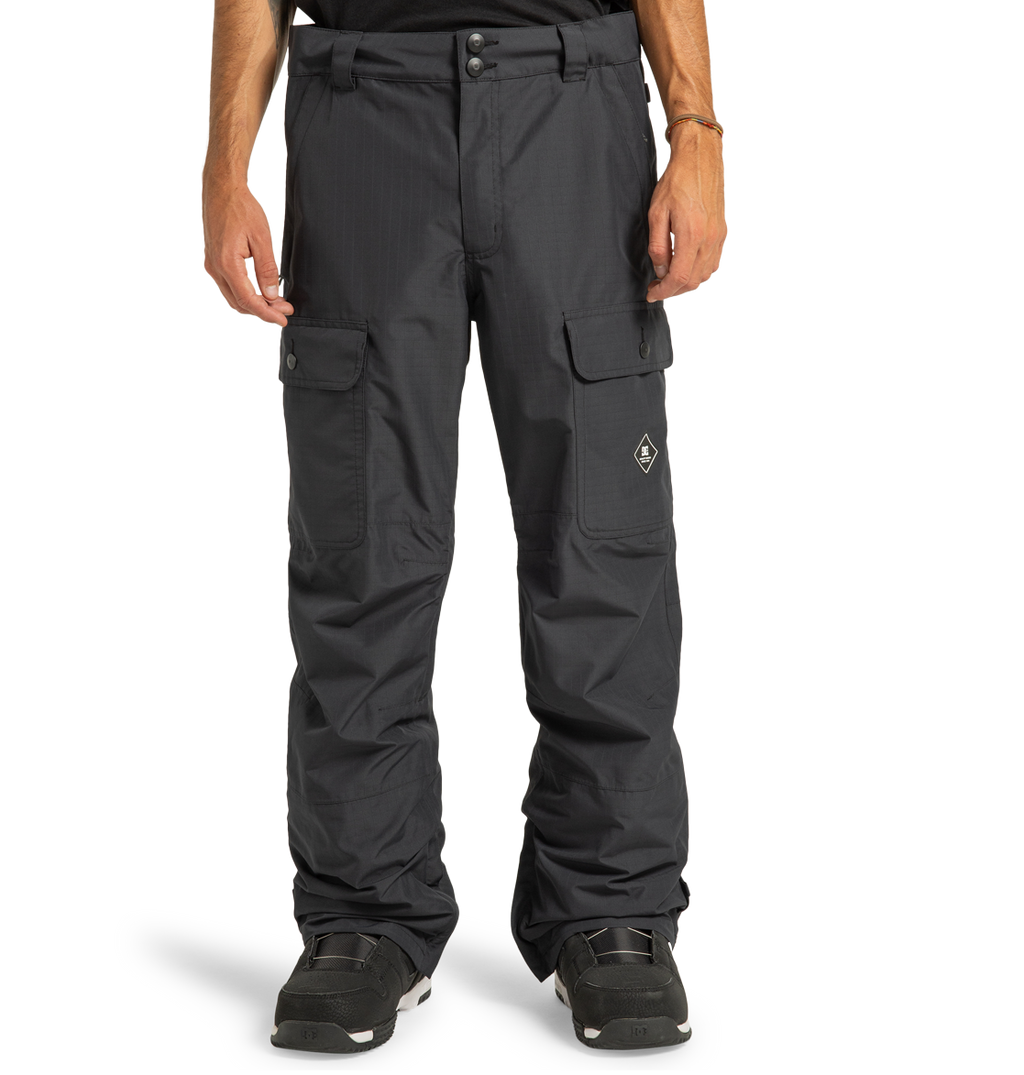 A person wearing DC Shoes Men’s Code Shell Pants, paired with black shoes and a bracelet, stands against a plain white background.