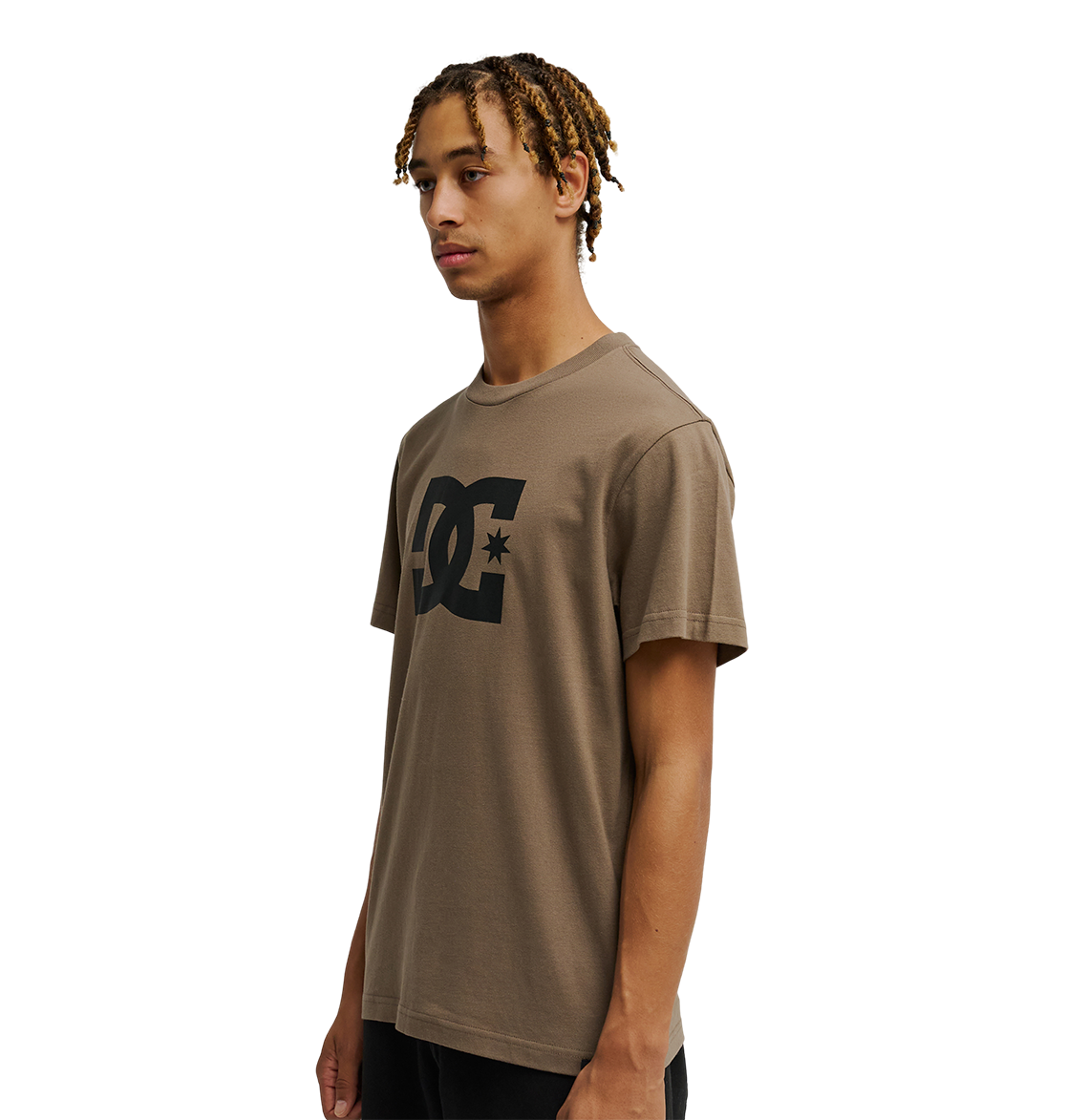 A person with short, blond-tipped braids wears a relaxed fit brown Men's DC Star Tee by DC Shoes, featuring a large black logo on the chest, standing against a plain white background.
