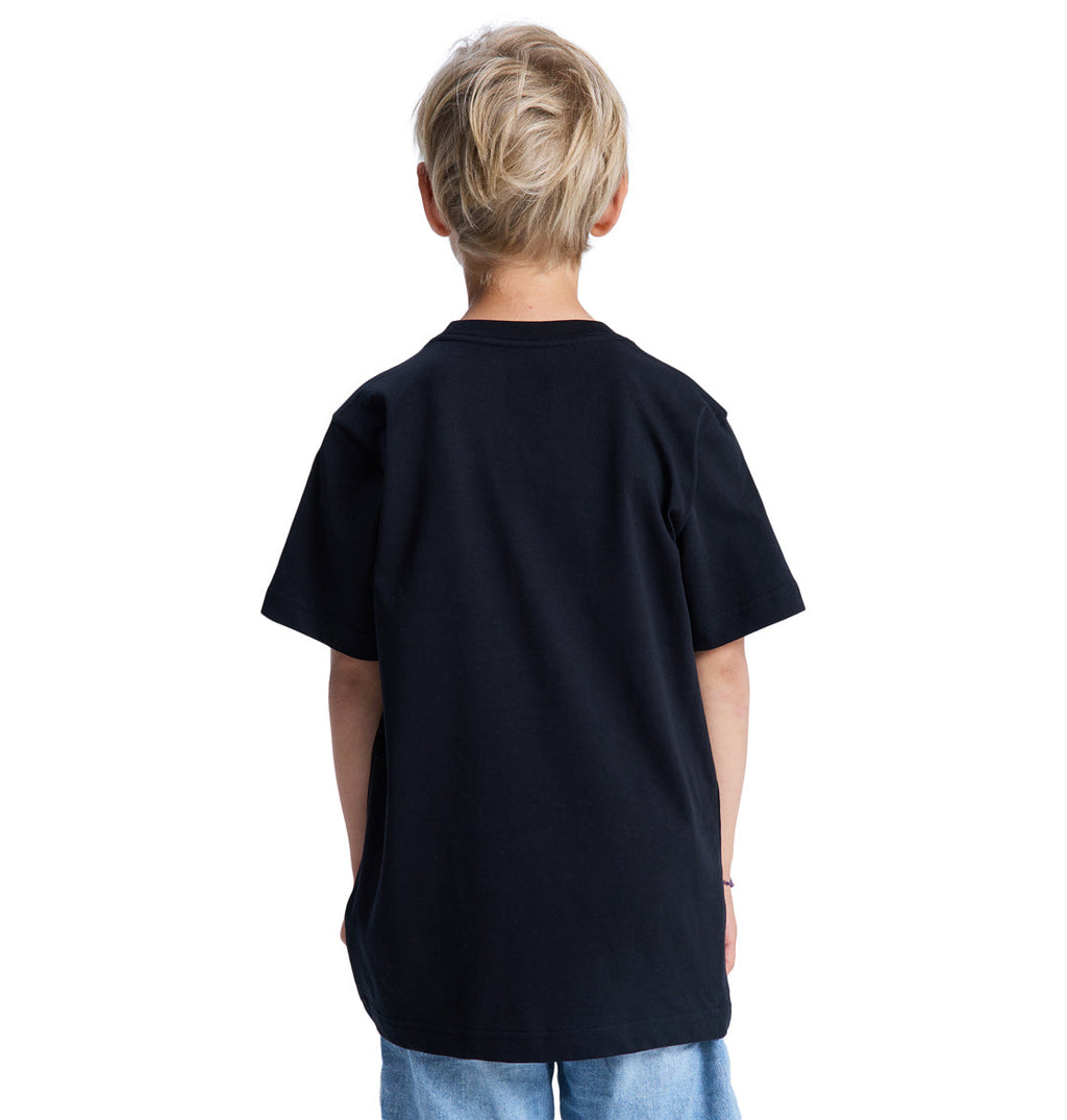 A young blond-haired child is seen from behind, wearing the Reebok DC Star Filled Ss Boy t-shirt and light blue jeans against a white background.