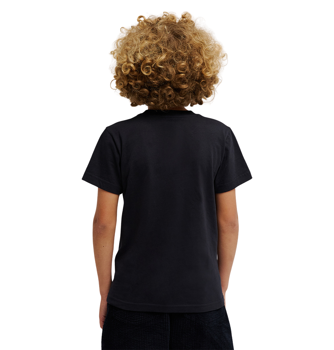 A child with curly blond hair, dressed in a relaxed fit DC Shoes Side Flame Tee Youth featuring subtle flame graphics, and dark shorts, stands with their back to the camera against a light, plain background.