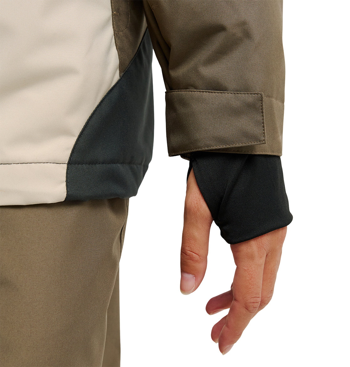 A close-up of a person wearing the DC Shoes Everfrost Jacket in tan and brown, featuring a black thumbhole sleeve that partially covers their hand.