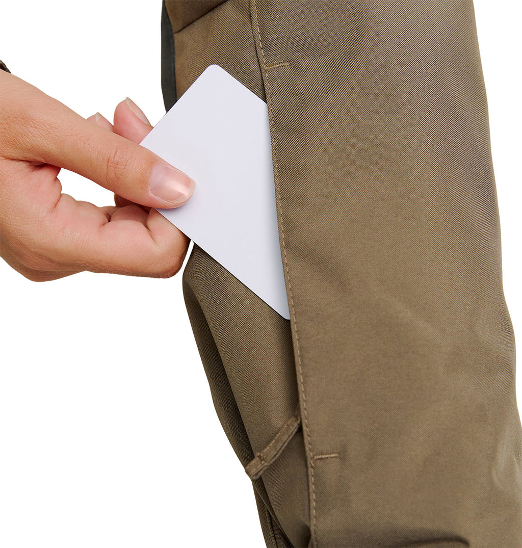 A hand slides a blank white card into the side pocket of brown pants, just beneath the hem of the DC Shoes Everfrost Jacket.