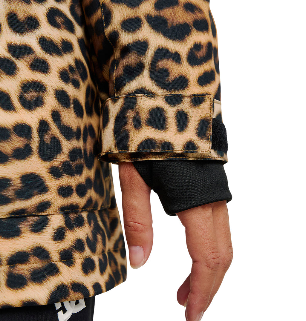 A close-up of a person’s hand wearing a black glove and the DC Shoes Cruiser Jacket, which features a brown and black leopard print pattern. The insulated sleeve of the Cruiser Jacket includes a strap with a black tab.