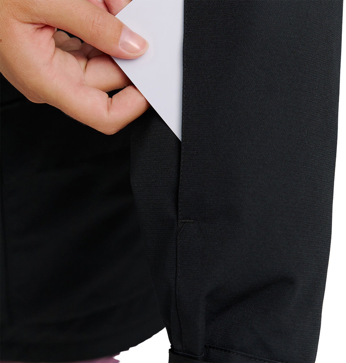 A hand slides a white card into a hidden pocket on the black sleeve of the DC Shoes Cruiser Jacket.