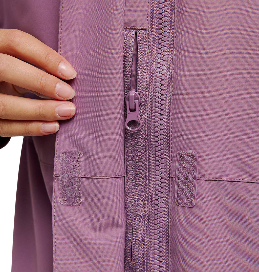 A close-up of a hand holding the edge of the DC Shoes Cruiser Jacket in mauve, highlighting its zipper and velcro fasteners.