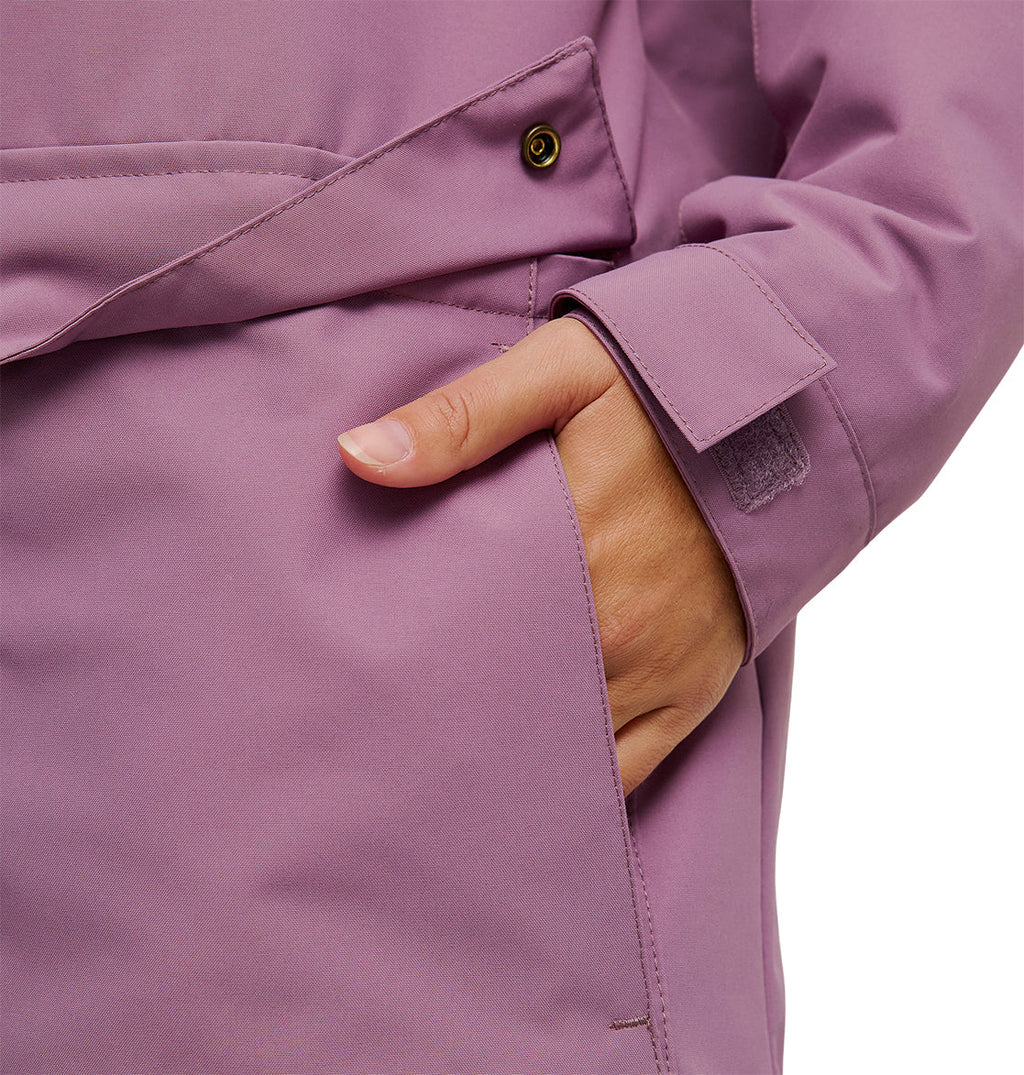 A person wearing the DC Shoes Cruiser Jacket in lavender, with one hand partially inside a pocket. The jacket features button detailing and a velcro strap on the cuff.