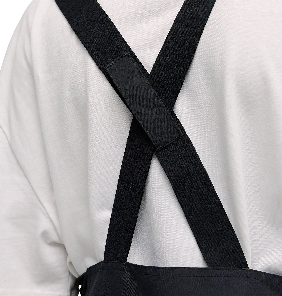 A close-up of a person wearing the DC Shoes Valiant Bib Pants, featuring crossed straps on their back and designed for breathable protection during any task.