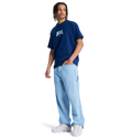 A person wears a navy DC Shoes t-shirt, white sneakers, and DC Shoes Men's Baggy Denim Carpenter Pant in a wide-leg fit, standing against a plain white background.