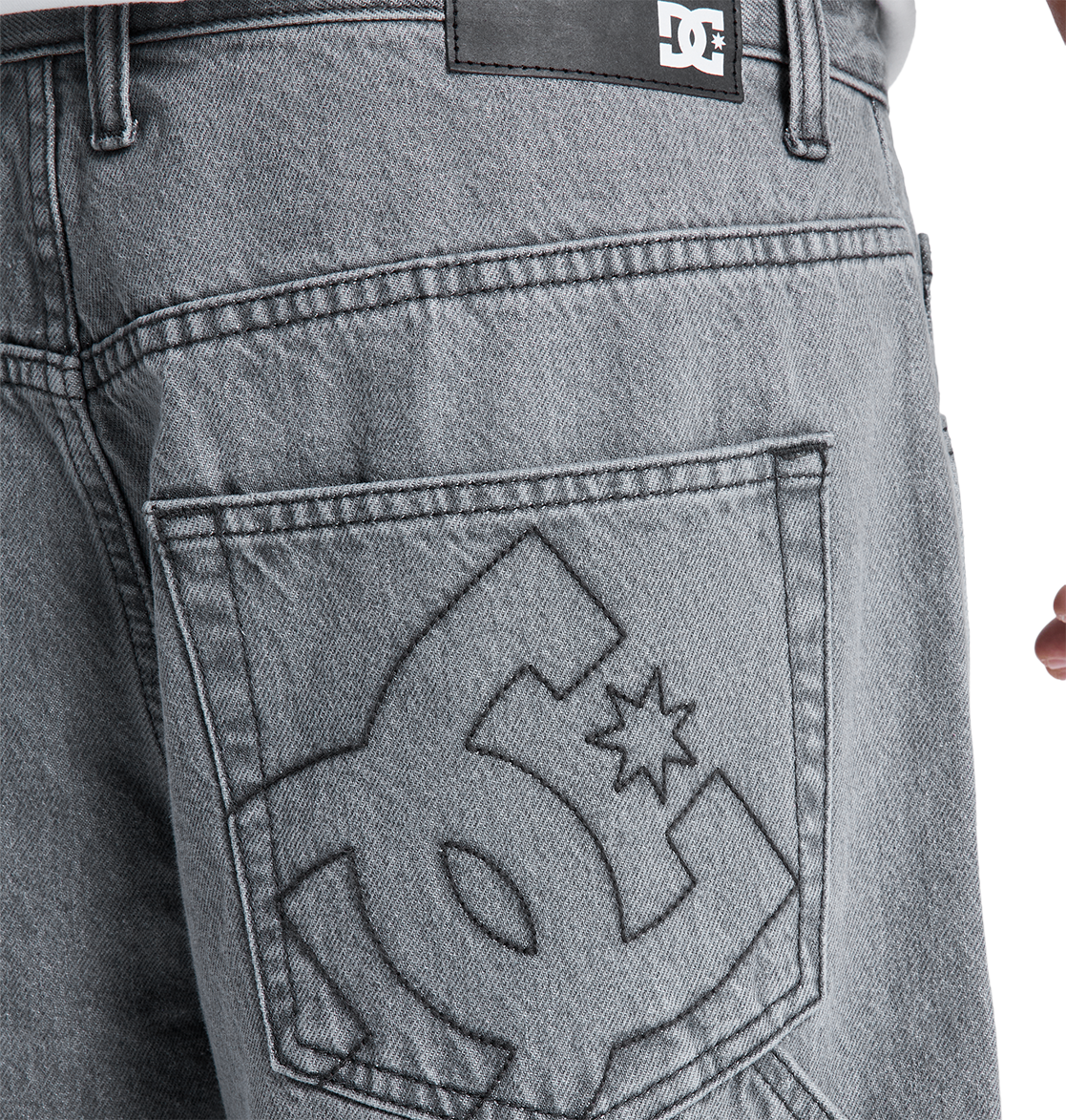 Close-up of the back pocket on DC Shoes Men's Baggy Denim Carpenter Pant in gray heavyweight denim, featuring a large embroidered logo and a black leather brand patch above the pocket, highlighting its wide-leg fit.