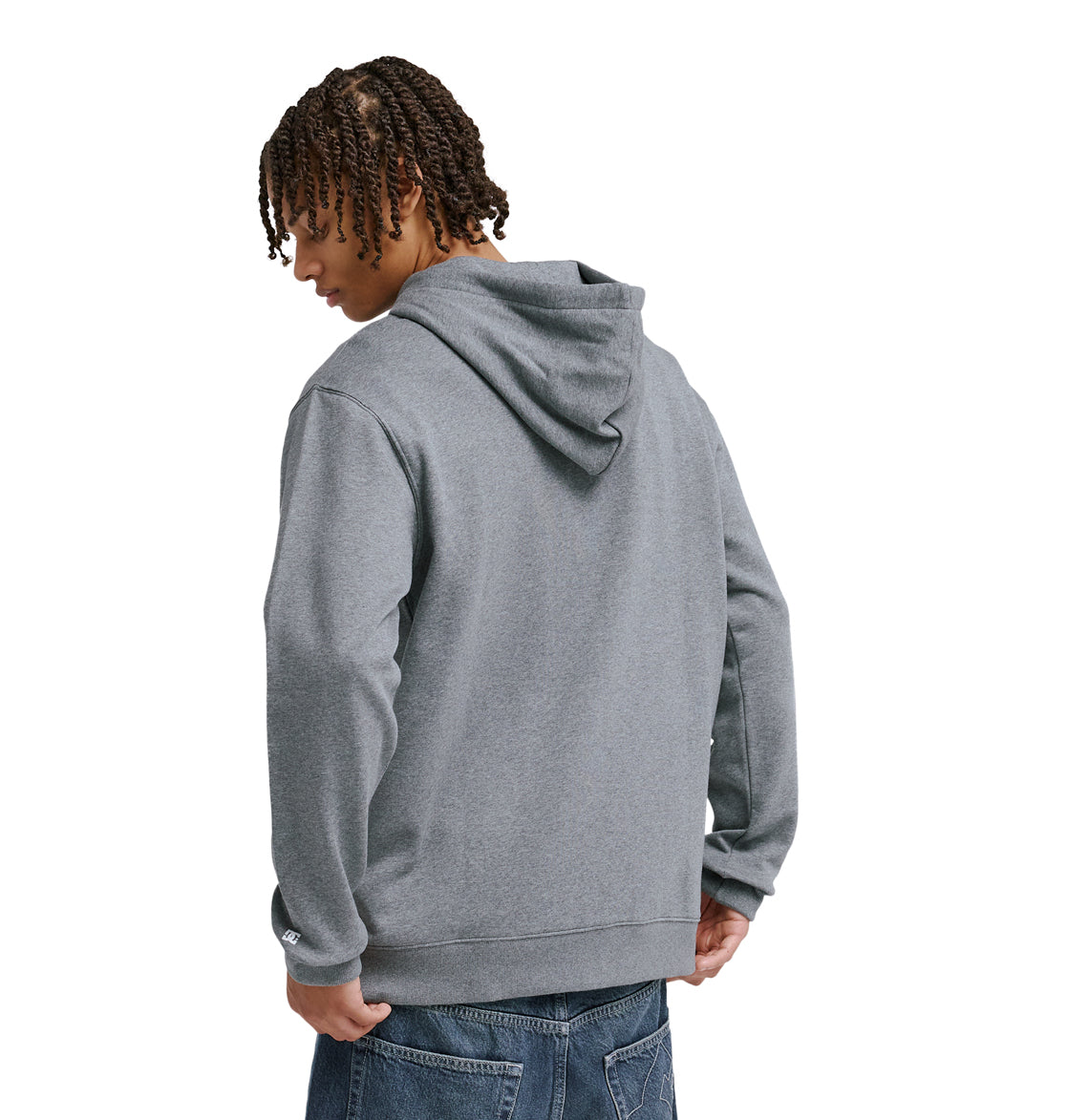 A person with short, twisted hair models the Reebok Lorion Zh gray hooded sweatshirt and blue jeans, standing with their back to the camera and head turned slightly to the side.