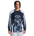 A person with braided hair wears the Reebok Sylem 2 Ls, a black and white long-sleeve shirt with a bold flame graphic, standing against a plain white background.