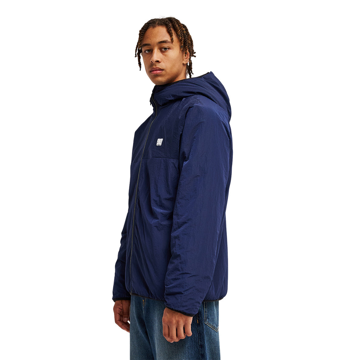 A person wearing the DC Shoes Coldstag Sherpa Reversible hooded jacket in blue and jeans stands facing slightly to the side against a white background.