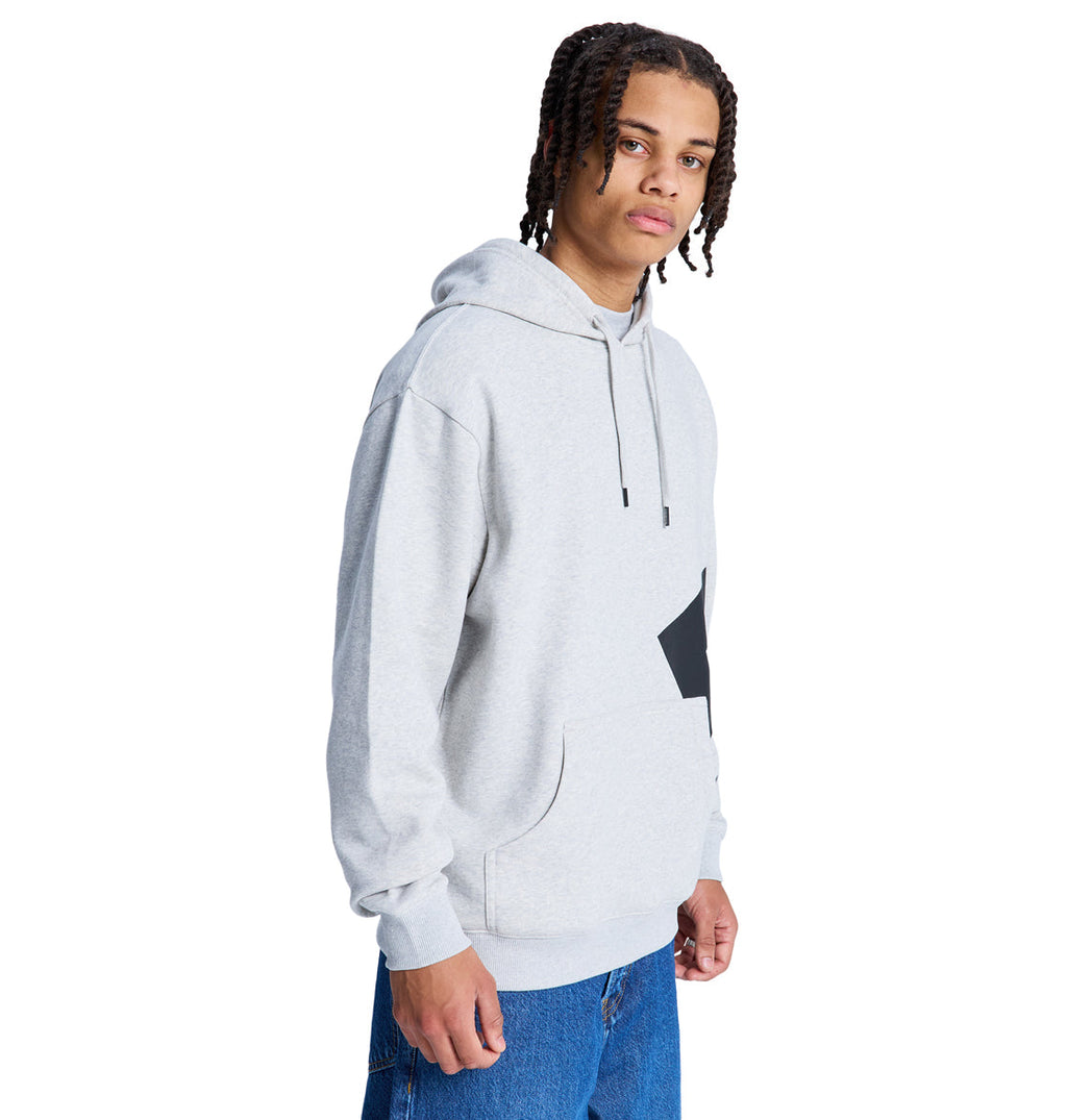 A person with braided hair models the Reebok Lanai Ph light gray hoodie with a front pocket and blue jeans, standing against a plain white background.