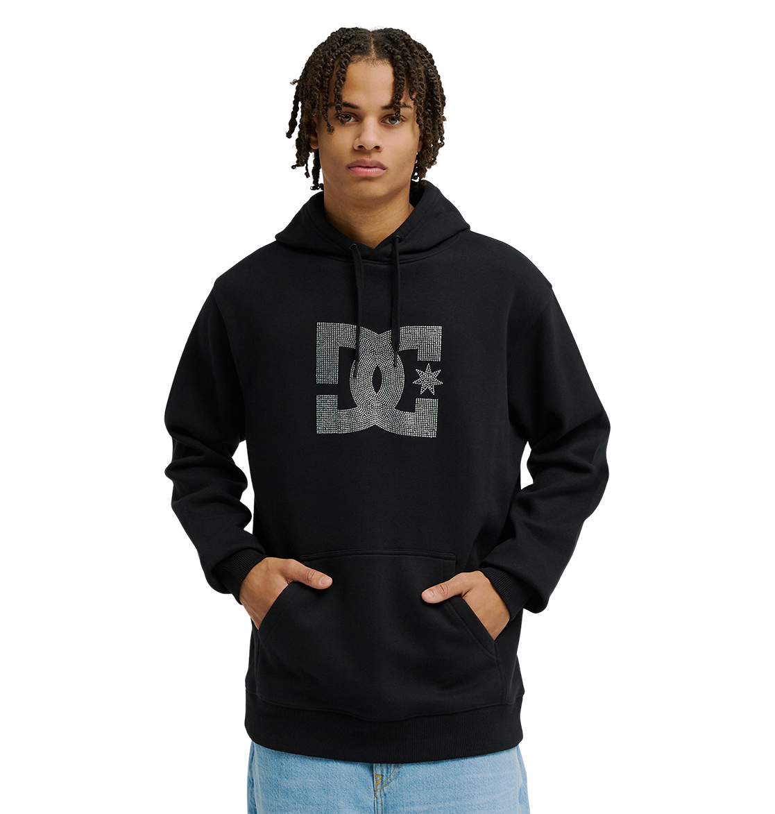 A person wearing the Men’s DC Strass Star Hoodie by DC Shoes, featuring a large rhinestone DC star logo on the front, stands with hands in the pocket. The black hoodie includes a drawstring hood for cozy fleece warmth, and is paired with light blue jeans.