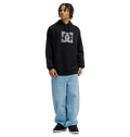 A person wearing the Men’s DC Strass Star Hoodie by DC Shoes, styled in black, pairs it with light blue baggy jeans and black sneakers while standing facing slightly to the right against a plain white background.