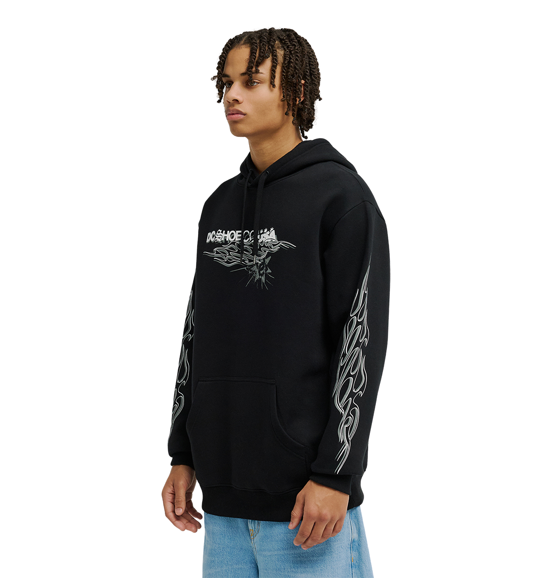 A person wearing the DC Shoes Men's Side Flame Hoodie, a black pullover with bold white DC graphics on the chest and sleeves, paired with light blue jeans, stands against a plain white background.