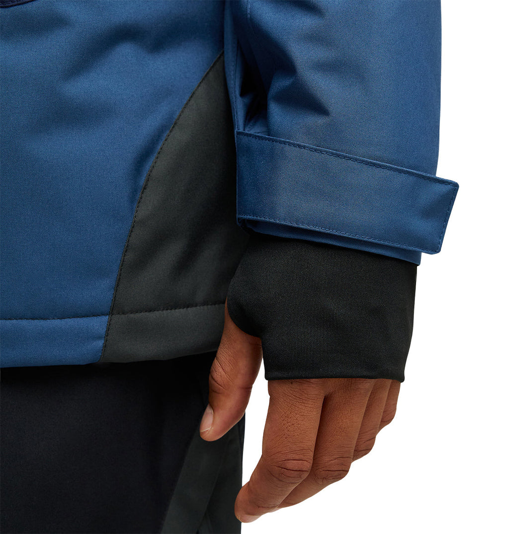 A close-up of a person’s hand in a blue and black DC Shoes Coldsmoke Jacket 10K, featuring a thumbhole in the black inner sleeve, highlights the jacket’s breathable protection.
