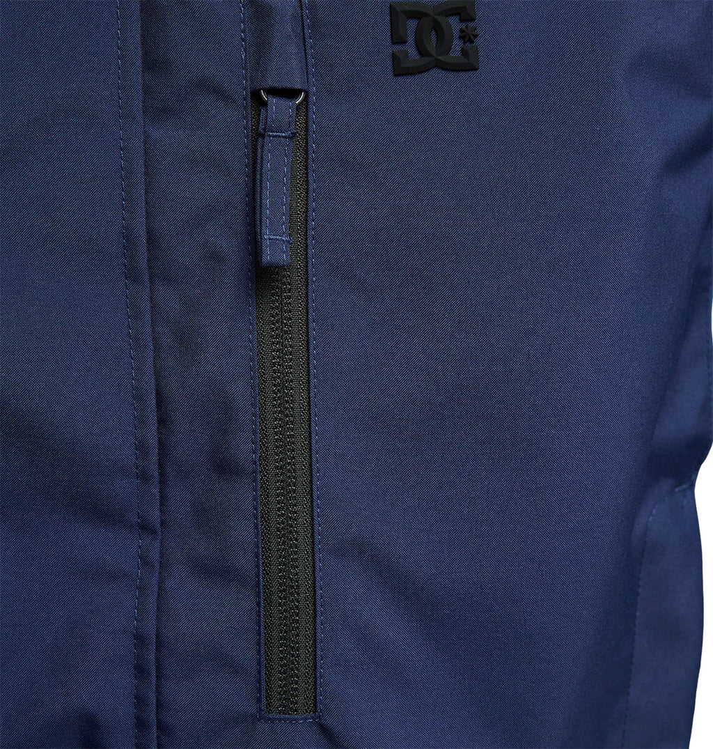 Close-up of the DC Shoes Coldsmoke Jacket 10K in navy blue, highlighting a vertical zippered pocket and a small black DC Shoes logo near the top right, designed with breathable protection for enhanced comfort and performance.