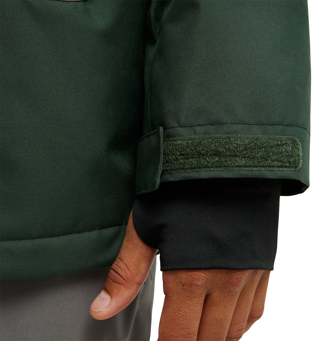 A close-up of a person’s hand wearing the DC Shoes Coldsmoke Jacket 10K, featuring a dark green color, Velcro cuff, and black inner sleeve for breathable protection. The hand is relaxed and resting by their side.